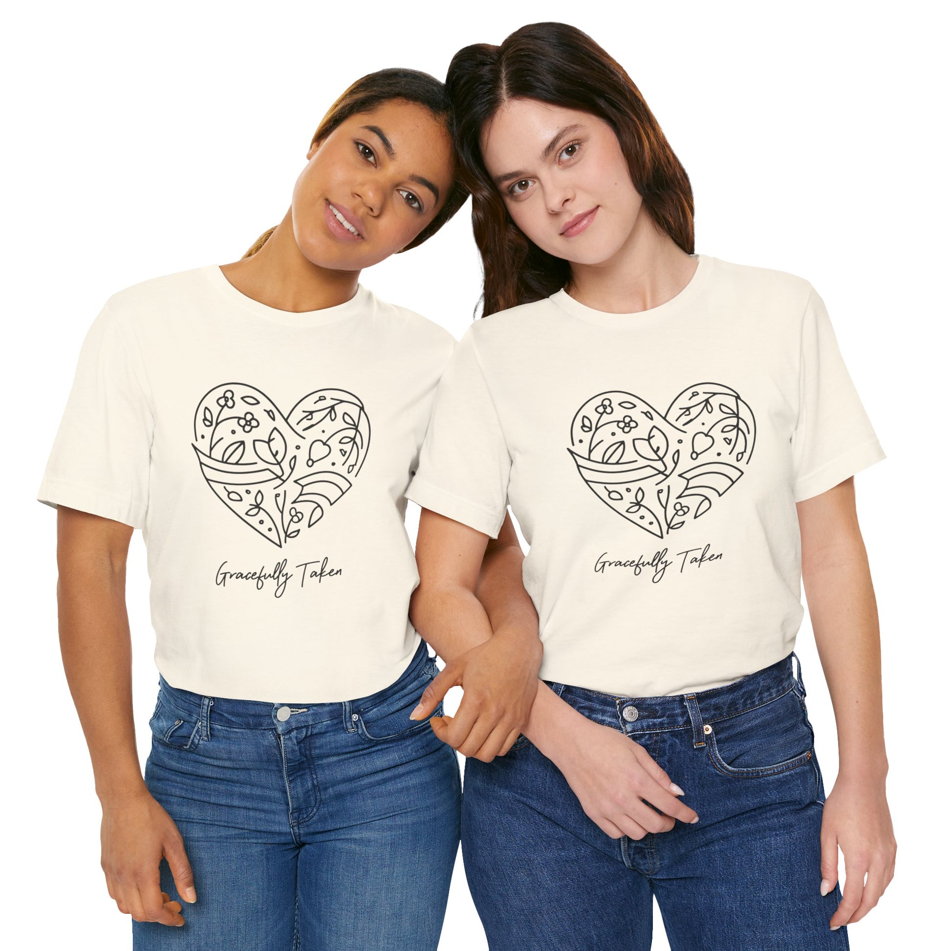 Two women wearing cream t-shirts with a heart design and text, standing close together on a white background.