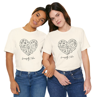 Two women wearing cream t-shirts with a heart design and text, standing close together on a white background.
