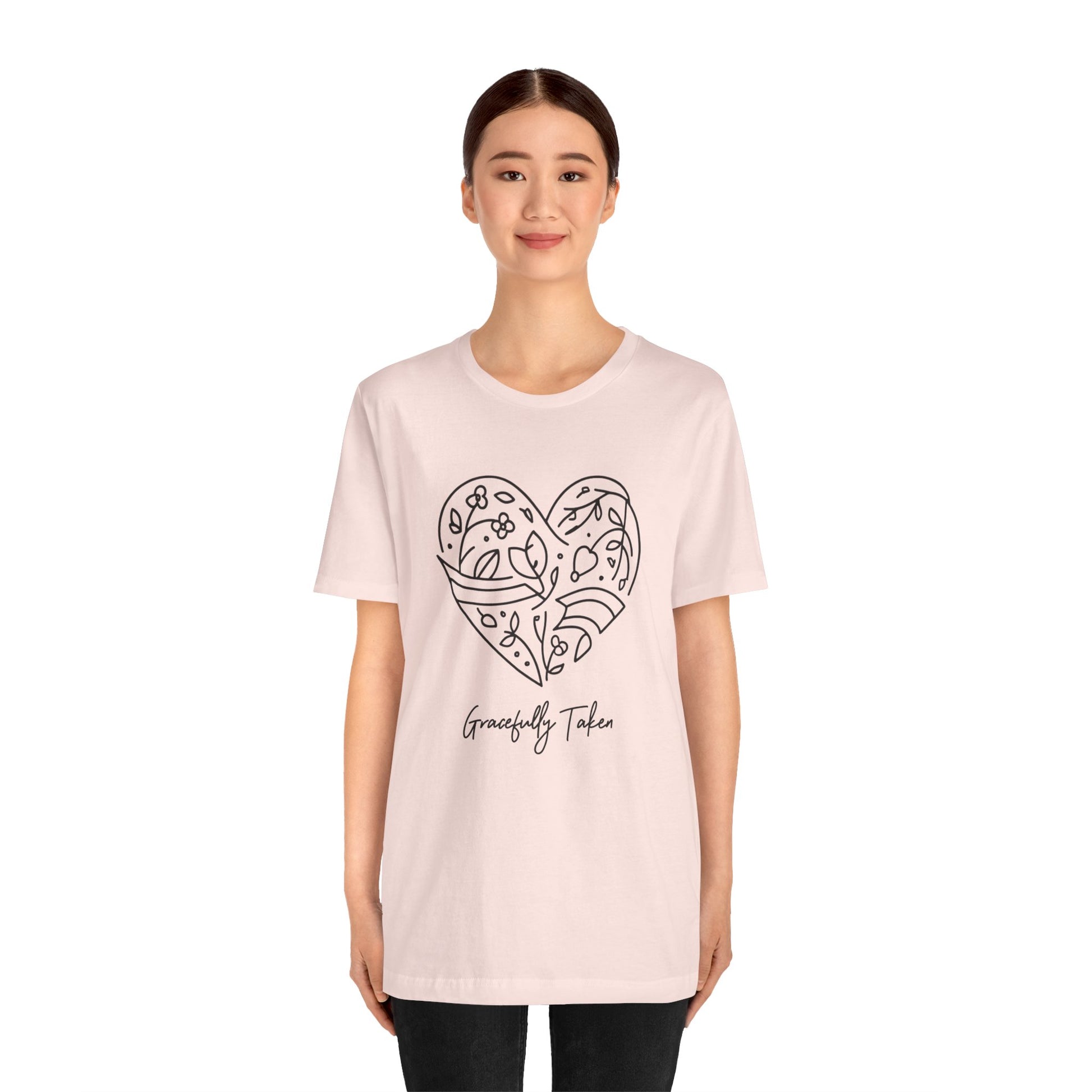 Person wearing a light pink t-shirt with a heart design and text on a white background