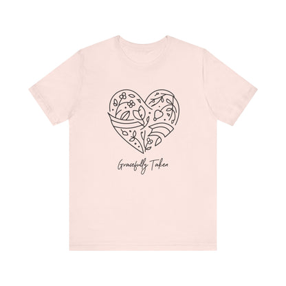 Pink t-shirt with a heart design and 'Gracefully Taken' text on a white background