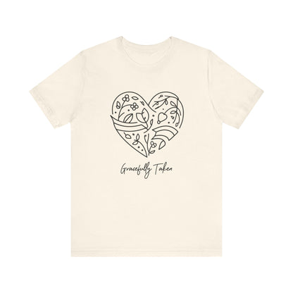Beige t-shirt with a heart design and 'Gracefully Taken' text on a white background