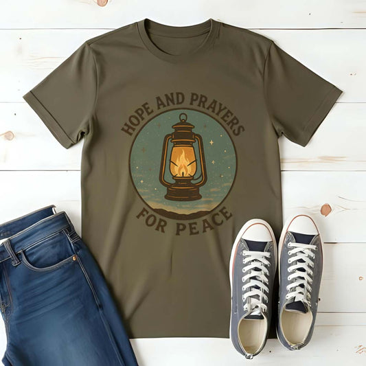 Olive green t-shirt with 'Hope and Prayers for Peace' design, blue jeans, and white sneakers on a wooden surface.