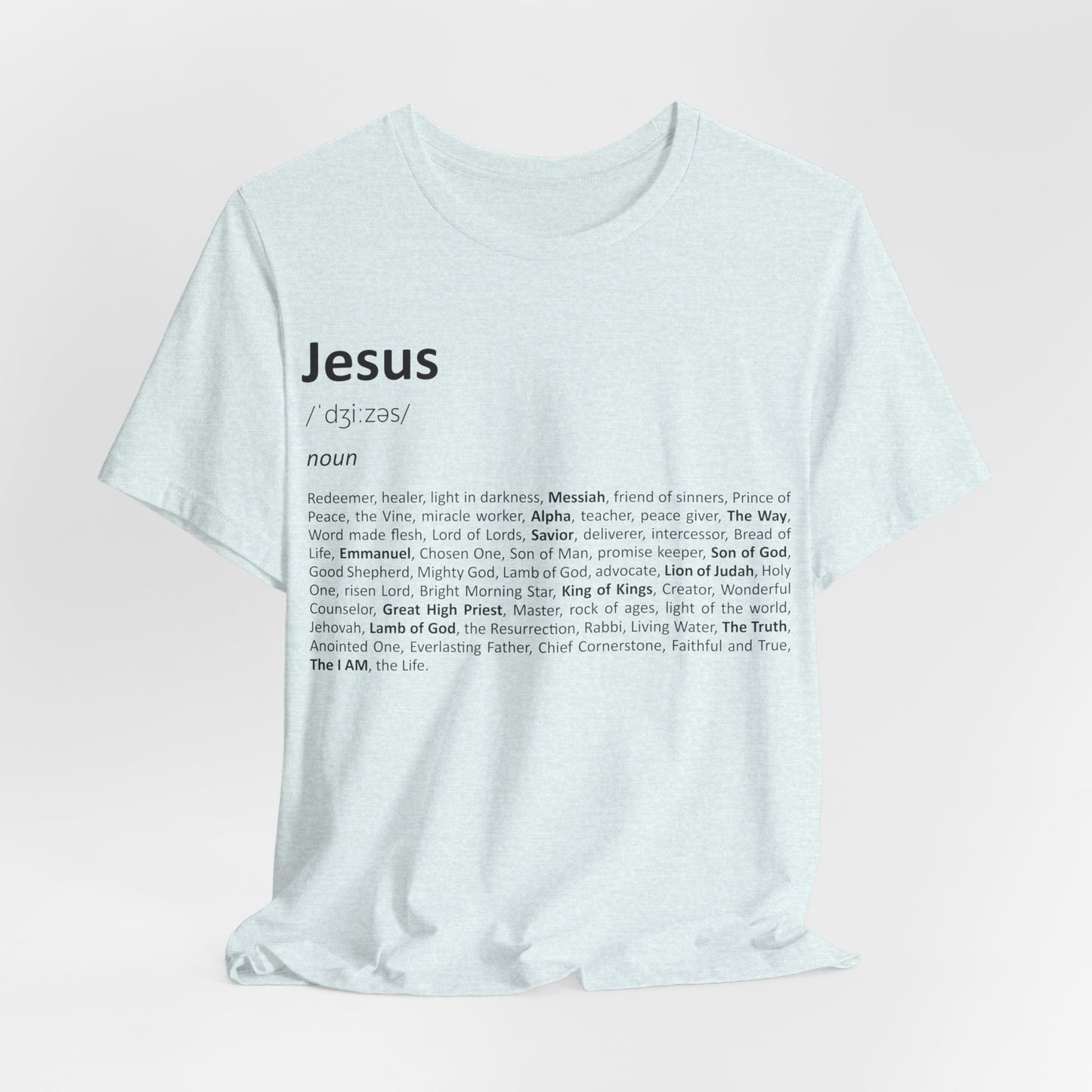 White t-shirt with 'Jesus' definition printed on it against a light pink background