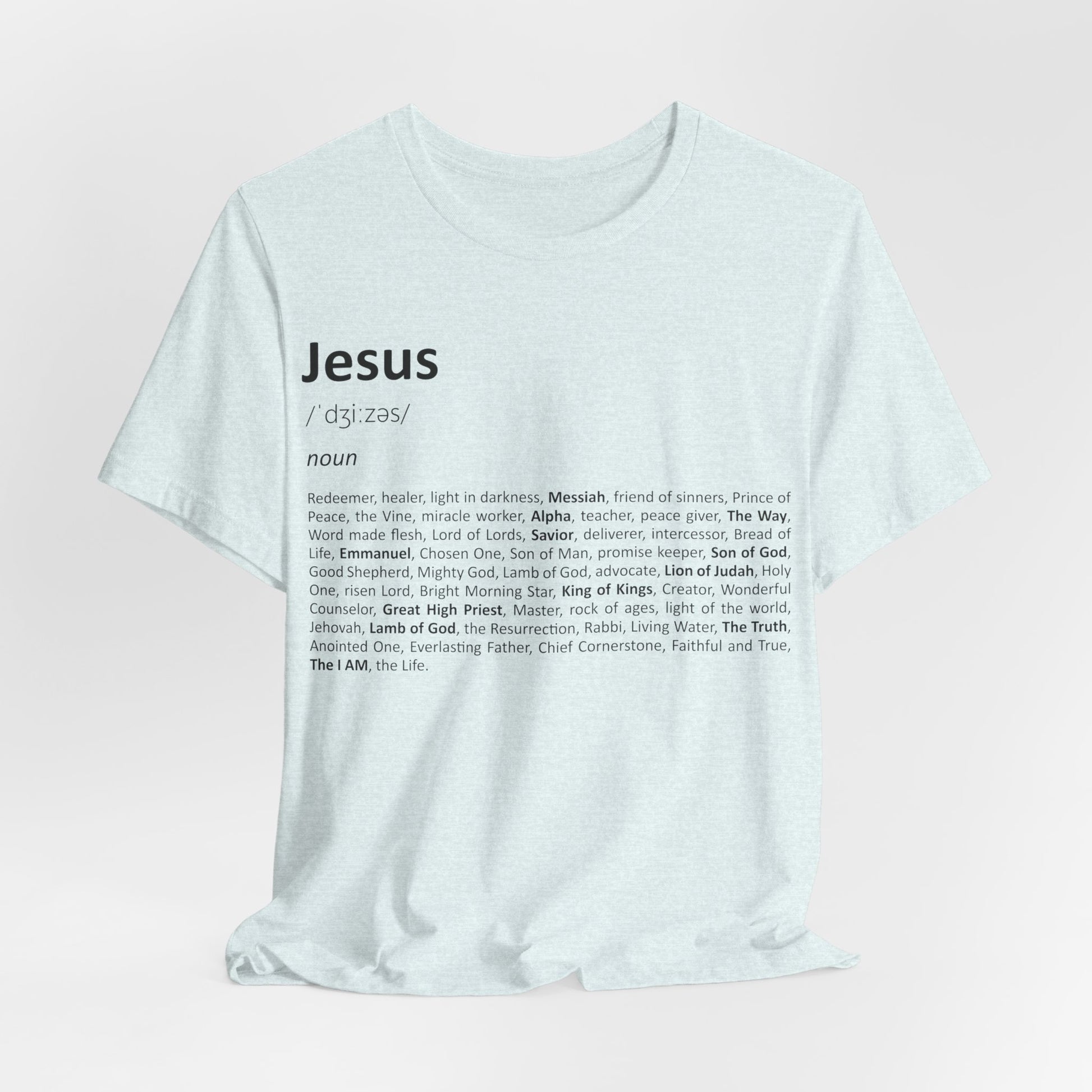 White t-shirt with 'Jesus' definition printed on it against a light pink background