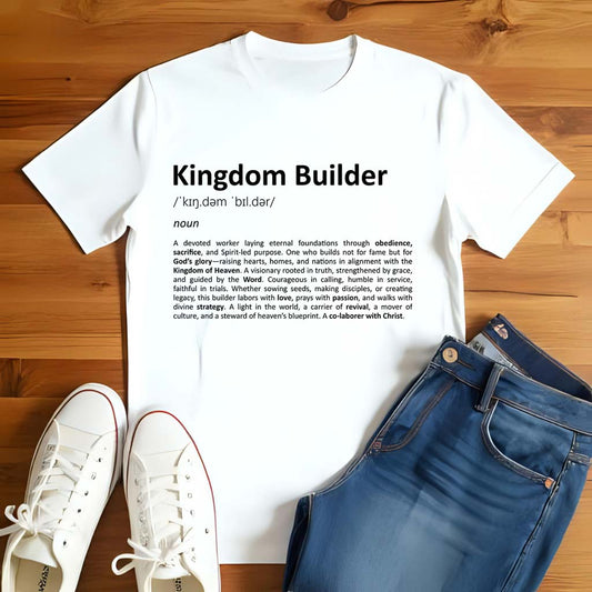 White t-shirt with 'Kingdom Builder' definition on a wooden surface with white sneakers and blue jeans.